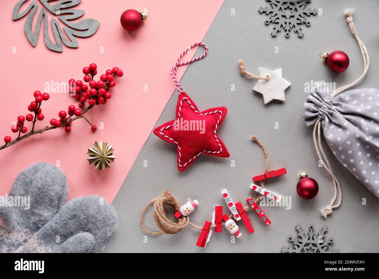 Regali naturali sostenibili per Natale zero rifiuti.Guanti, giocattoli morbidi, pioli di legno e bacche naturali. Carta a strati grigio rosa, vista dall'alto, disposizione piatta. Foto Stock