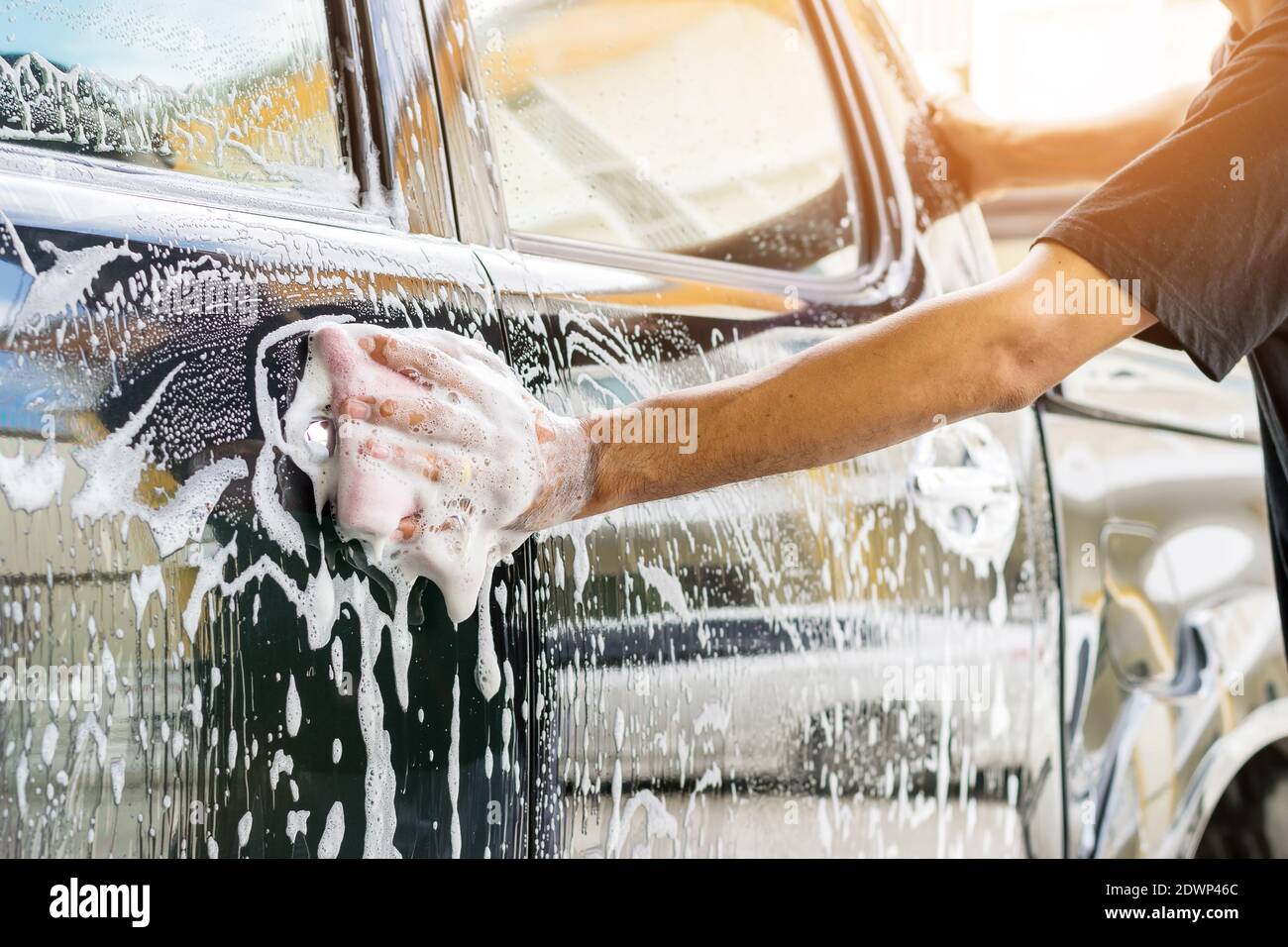 Il personale addetto all'assistenza auto pulisce un'auto con spugne e concetti di dettaglio e valeting per autolavaggio. Foto Stock