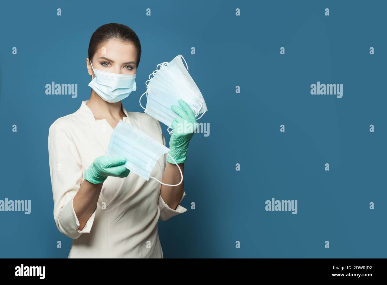 Medico che dà maschera medica protettiva su sfondo blu, medicina, sicurezza e virus covid-19 concetto di protezione Foto Stock