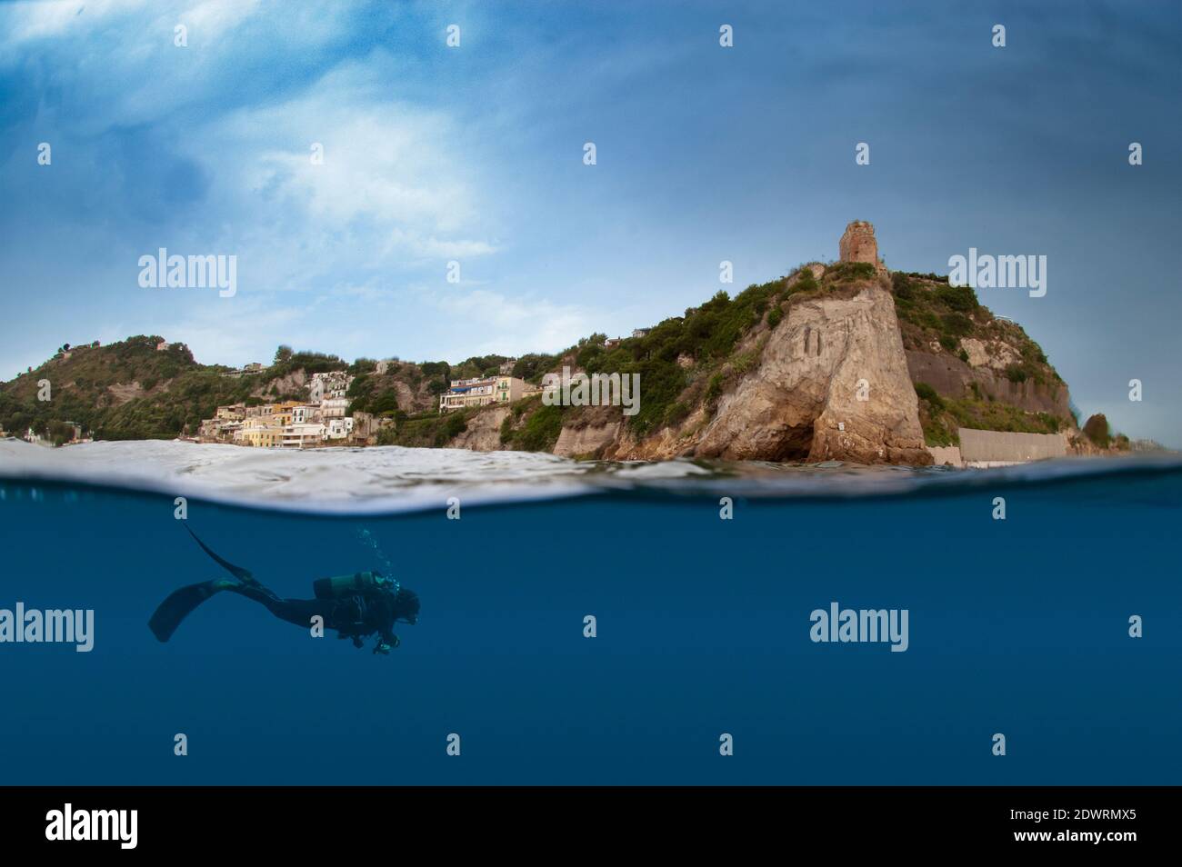 Mezzo sotto e sopra l'acqua foto di subacqueo nuotare sott'acqua con antiche rovine del tempio romano in lontananza. Baiae, Pozzuoli, Napoli. Italia Foto Stock