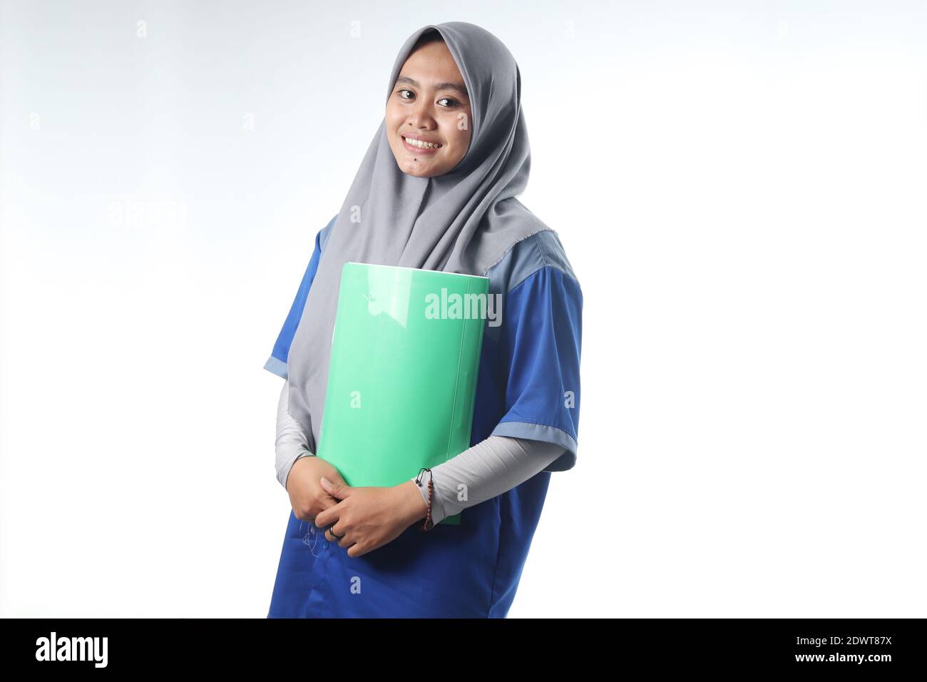 Ritratto di una donna asiatica che indossa abiti da lavoro o da scuola. Una donna velata che porta un libro di rapporto. Imparare o lavorare concetti fotografici con gli expres felici Foto Stock