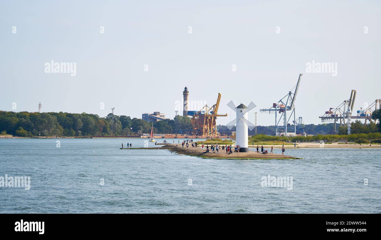 Turisti al faro mulino, il punto di riferimento della città di Swinoujscie, sullo sfondo il porto Foto Stock