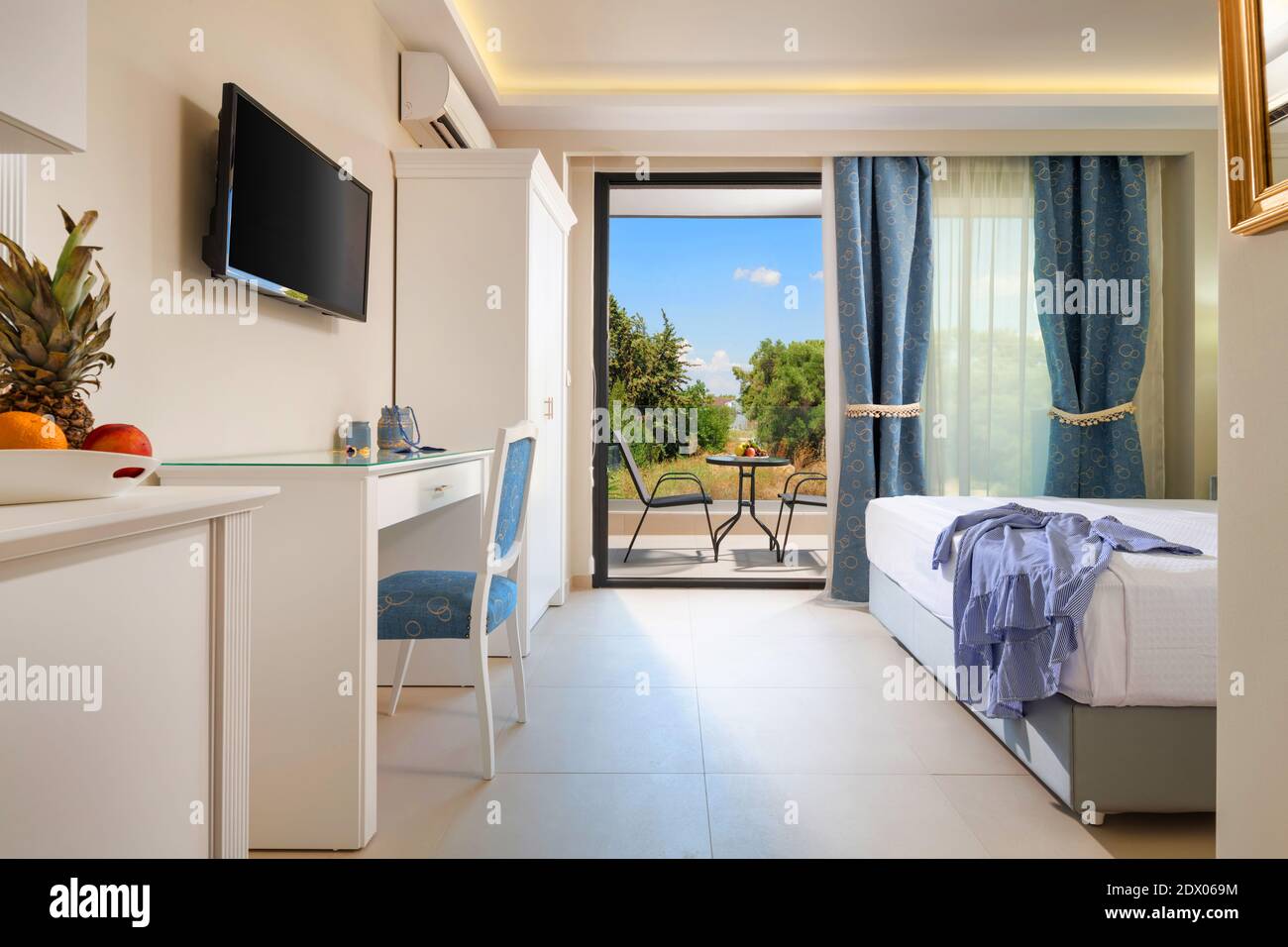 Interni in stile classico di una splendida camera da letto bianca con grande apertura finestra - porta di vetro per la vista giardino estivo con elegante mobili da terrazza Foto Stock