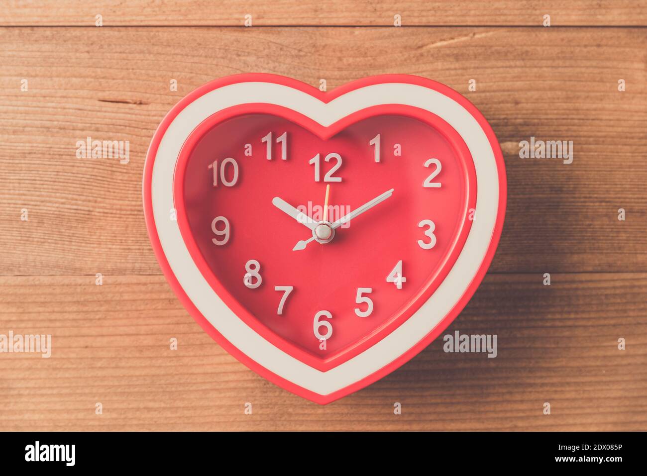 Direttamente sopra Tiro di orologio a forma di cuore rosso su tavolo in  legno Foto stock - Alamy