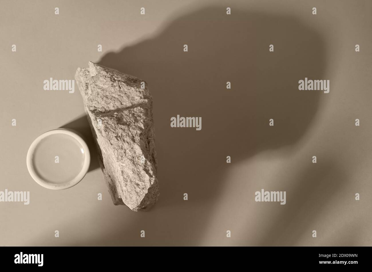 Podio rotondo in vetro e pietra su sfondo beige con ombre, posto per il vostro prodotto, monocromatico Foto Stock
