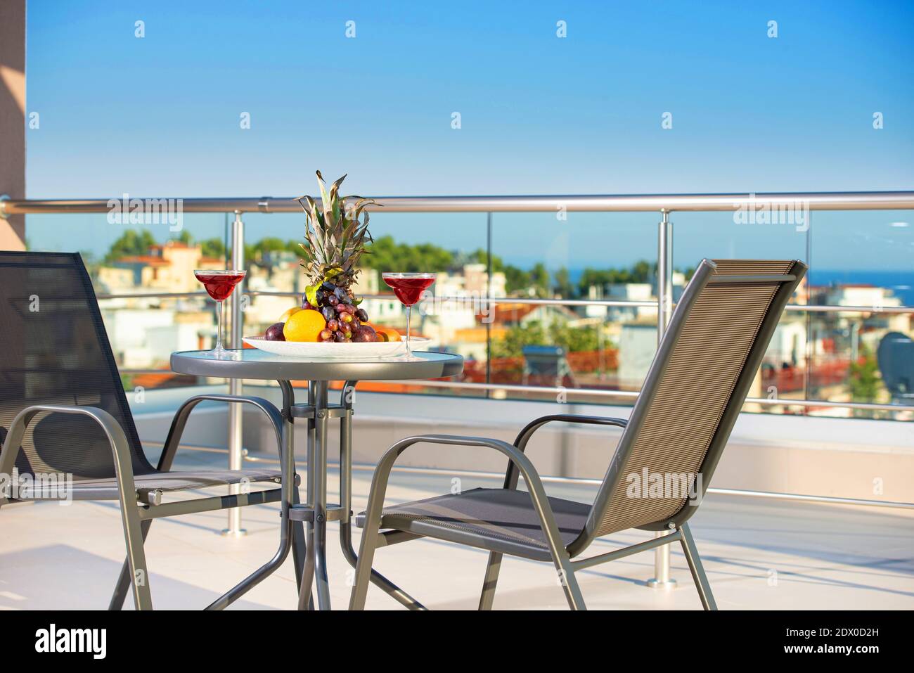 Primo piano di patio moderno con frutta, vino, tavolo, sedie sul tetto terrazza di lusso vista mare resort con cielo blu spazio copia Foto Stock