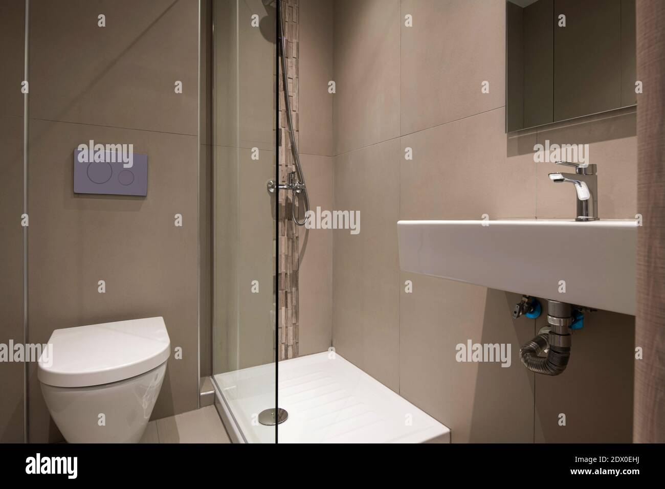 Interni contemporanei di un piccolo e moderno bagno con tubazioni bianche e. decorazione con piastrelle in pietra a mosaico grigio Foto Stock