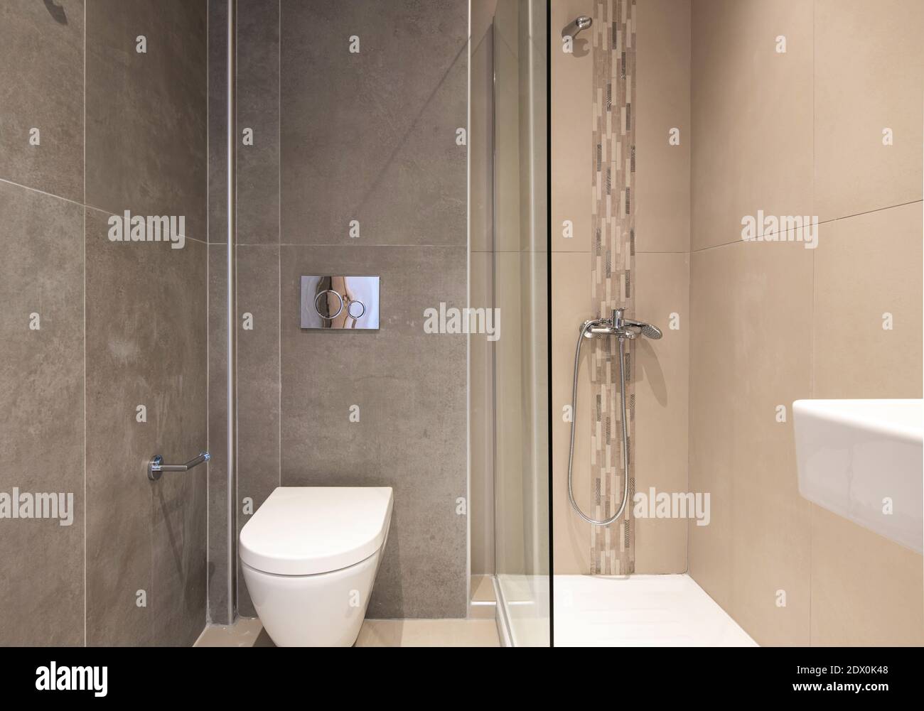 Vista frontale del bagno di piccole dimensioni in stile moderno. Interno della toilette piastrellato di mosaico beige e piastrelle in grande scala con struttura in marmo grigio Foto Stock