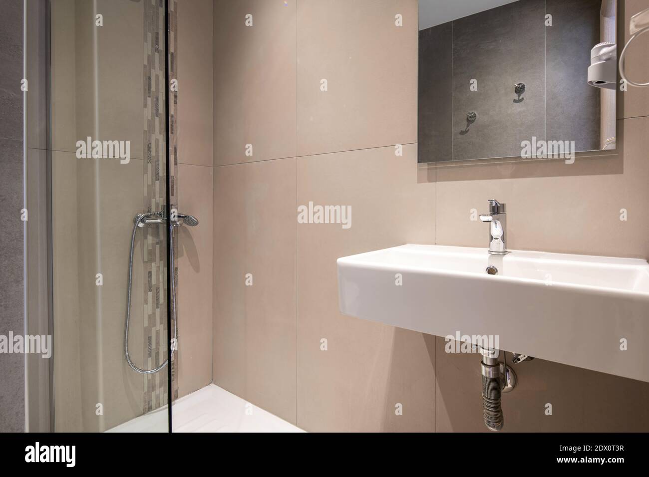 Interni moderni di una piccola stanza da bagno con doccia in vetro e lavandino rettangolare bianco, mosaico testurizzato e piastrelle in pietra piena Foto Stock