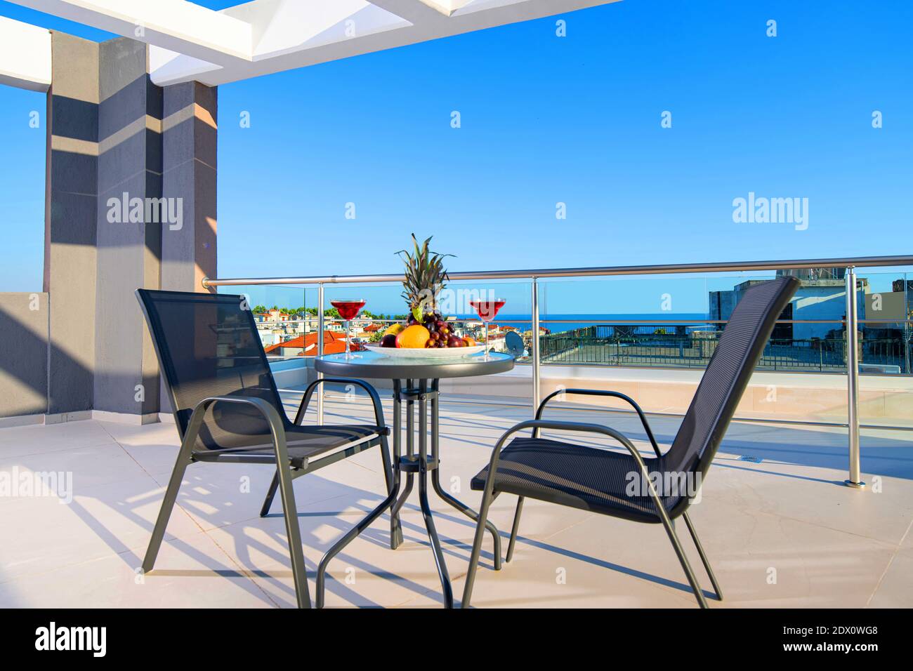 Concetto di ricreazione panorama di patio moderno con frutta, vino, tavolo, sedie sul terrazzo sul tetto del resort di lusso vista mare Foto Stock