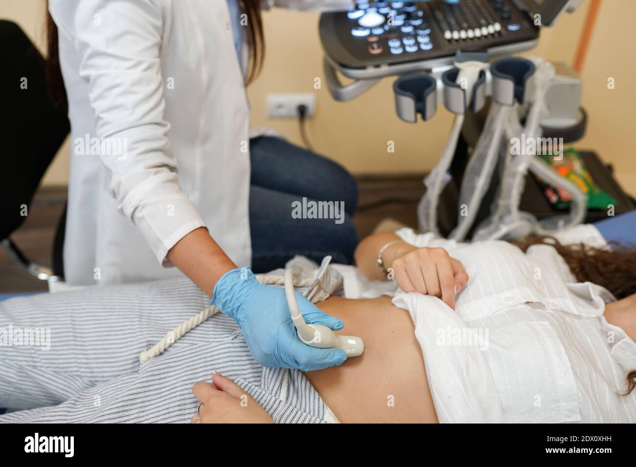 medico che sposta il trasduttore a ultrasuoni sul ventre di una donna mentre si guarda sullo schermo dell'ospedale Foto Stock