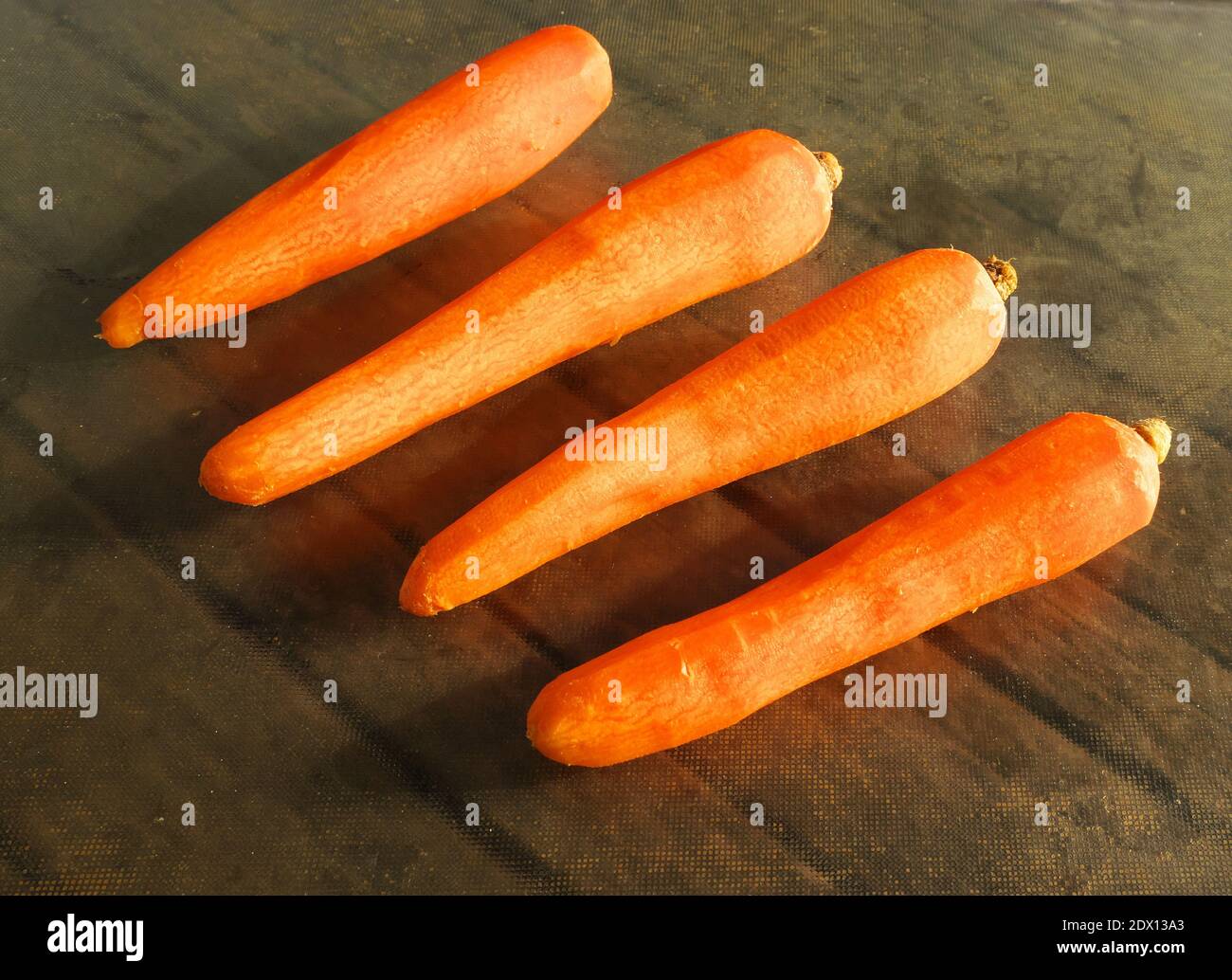 Foto di quattro carote sbucciate pronte per essere cotte Foto Stock