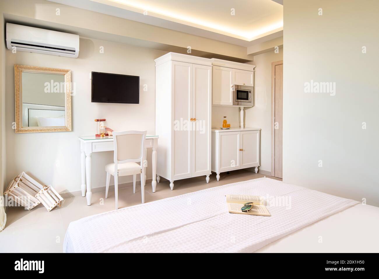 Interni bianchi ed eleganti di un piccolo monolocale con mobili in legno dal design classico in un moderno appartamento alberghiero. Foto Stock