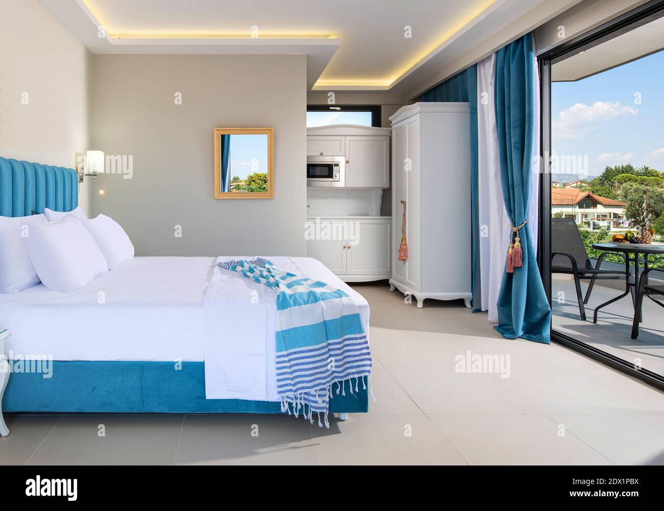 Interni bianchi e blu di stile classico elegante complesso di appartamenti per vacanze estive. Terrazza con finestra aperta nella camera da letto con splendida vista Foto Stock