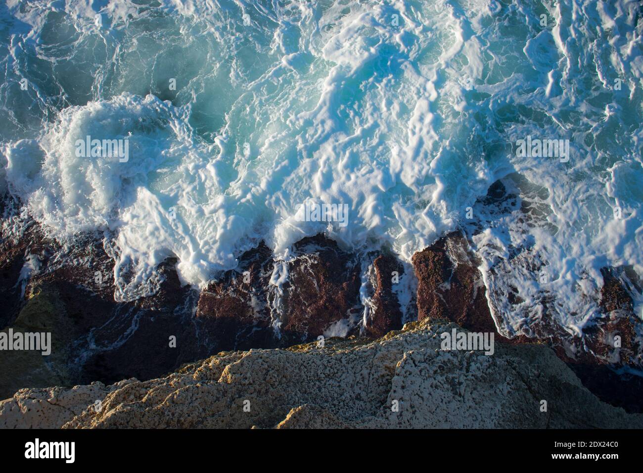 Vista aerea di una scogliera mentre le onde colpiscono la riva in una giornata di sole Foto Stock