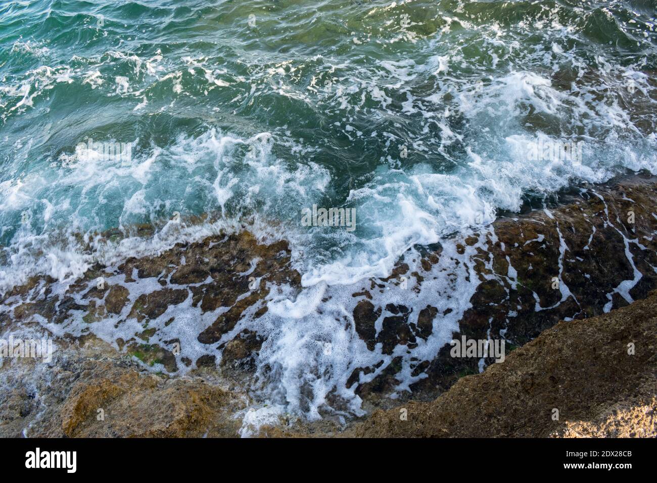 Onde marine che colpiscono la riva nella zona costiera di Alicante, Spagna Foto Stock