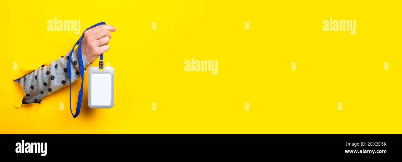 La mano femmina tiene un badge vuoto sul nome su uno sfondo giallo. Banner. Foto Stock