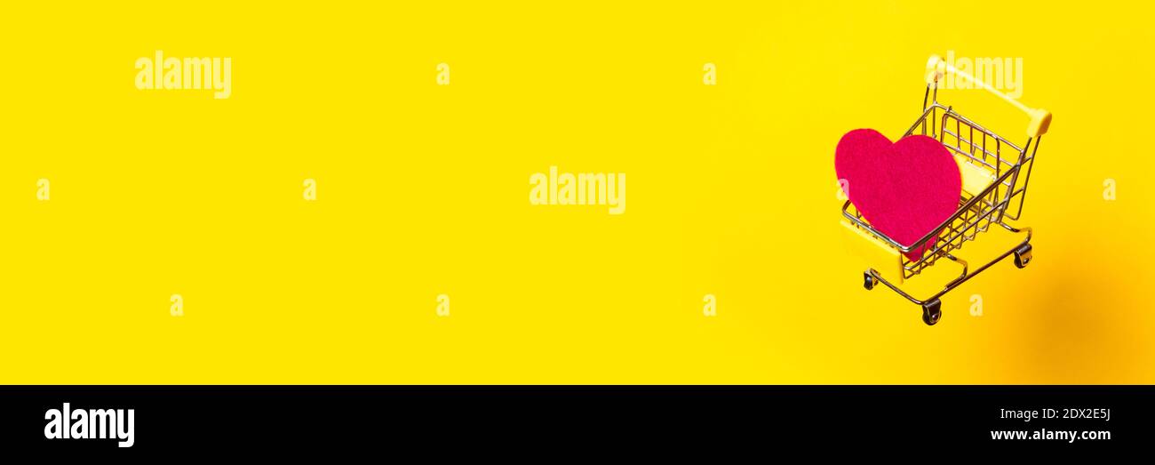carrello con cuore rosa vola su uno sfondo giallo luminoso. Banner. Foto Stock