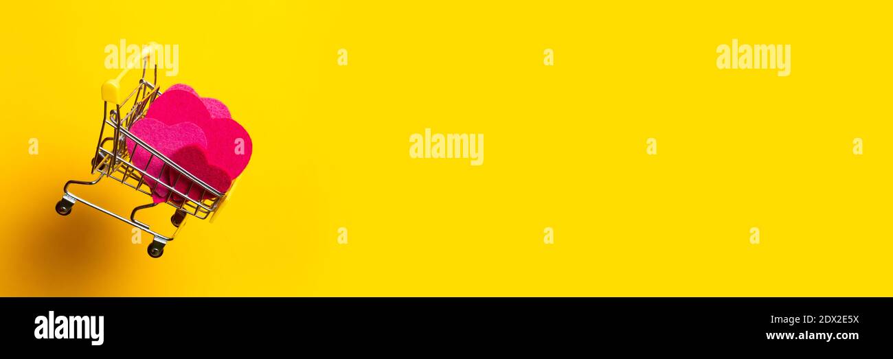 carrello con cuori rosa vola su uno sfondo giallo luminoso. Banner. Foto Stock