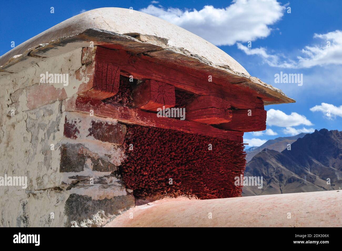 Dettaglio di una vecchia costruzione storica di mura in un tempio a Lhasa, Tibet. Il muro è di fronte a pietra e riempito di paglia. Verniciato di rosso, il coperchio è Foto Stock