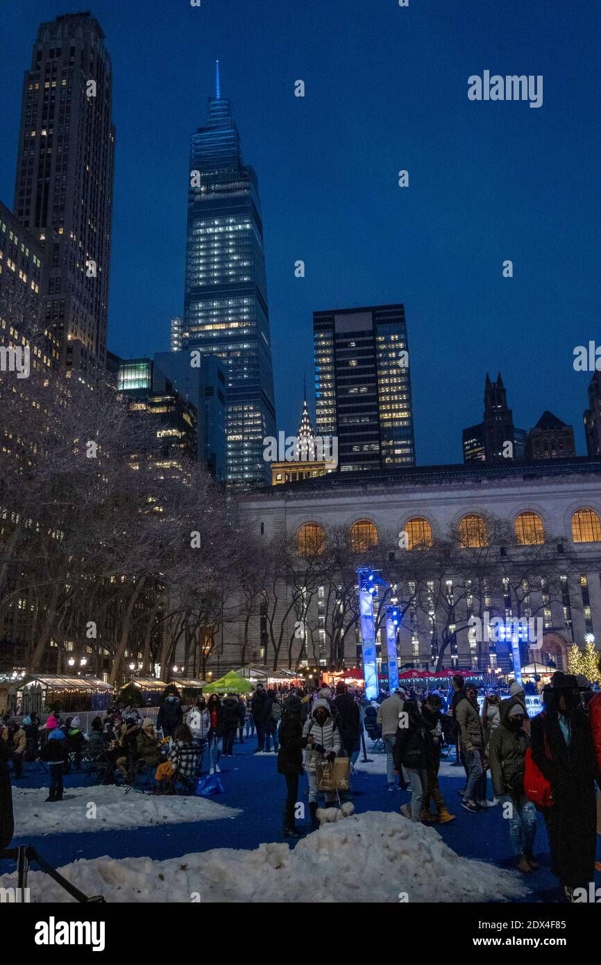 Le persone che si godono gli alberi di Natale luminosi nel villaggio vacanze di Bryant Park in una serata di vino, New York City, USA Foto Stock