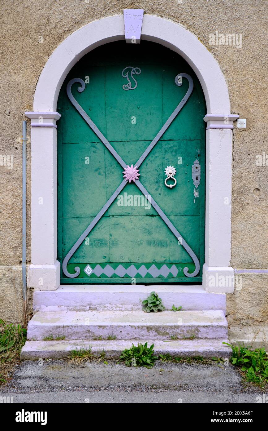 Porta in legno verde d'epoca piena di design in ferro ornato, con portico a volta Foto Stock