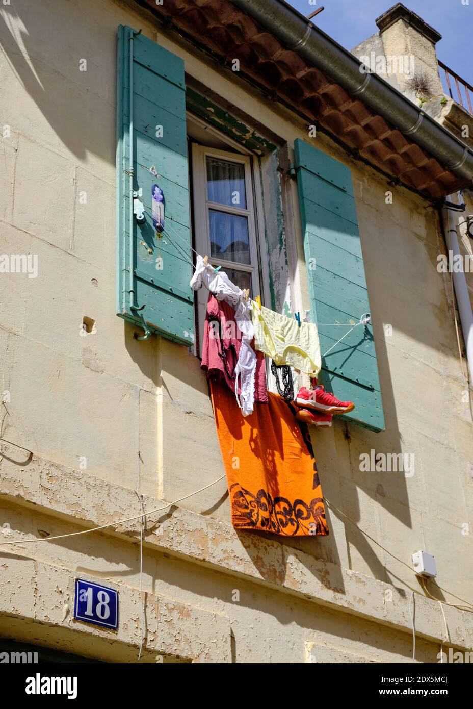 Lavanderia appesa ad asciugare dalla finestra con persiane a Arles, Francia Foto Stock