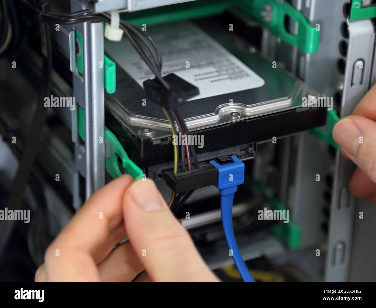 Un disco rigido a memoria magnetica viene visualizzato come installato o rimosso dal case di una torre del computer in una vista in primo piano. Foto Stock