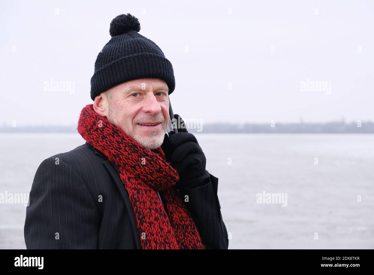 Ritratto di un anziano che parla sul telefono cellulare sul lago ghiacciato. Foto Stock