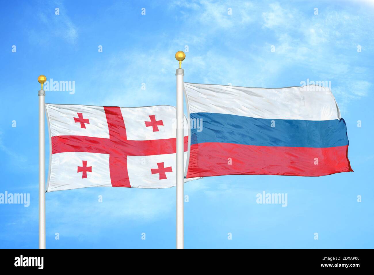 Georgia e Russia due bandiere su flagpoli e cielo blu Foto Stock