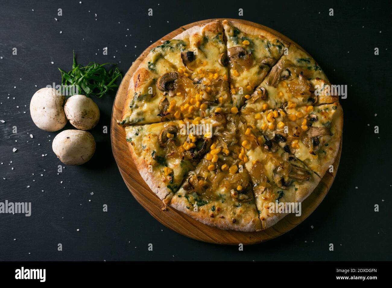 vista dall'alto deliziosa pizza con ingredienti mozzarella, funghi di cipolle caramellate al mais con una base di salsa bianca su un bac nero rustico in legno Foto Stock