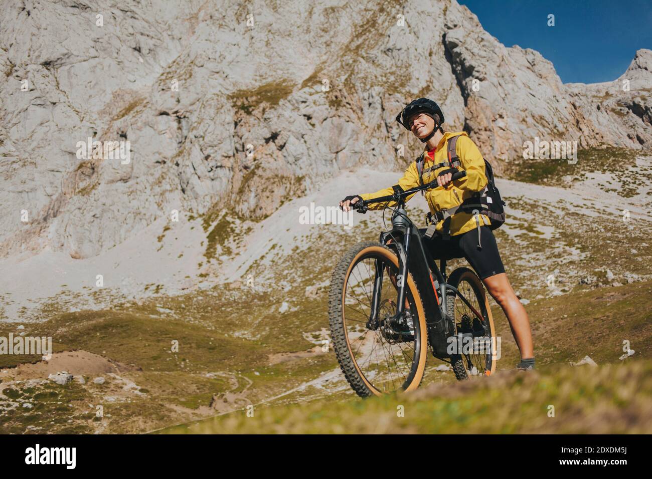 Sorridente ciclista femminile con mountain bike in giornata di sole al Parco Nazionale di Picos de Europa, Cantabria, Spagna Foto Stock