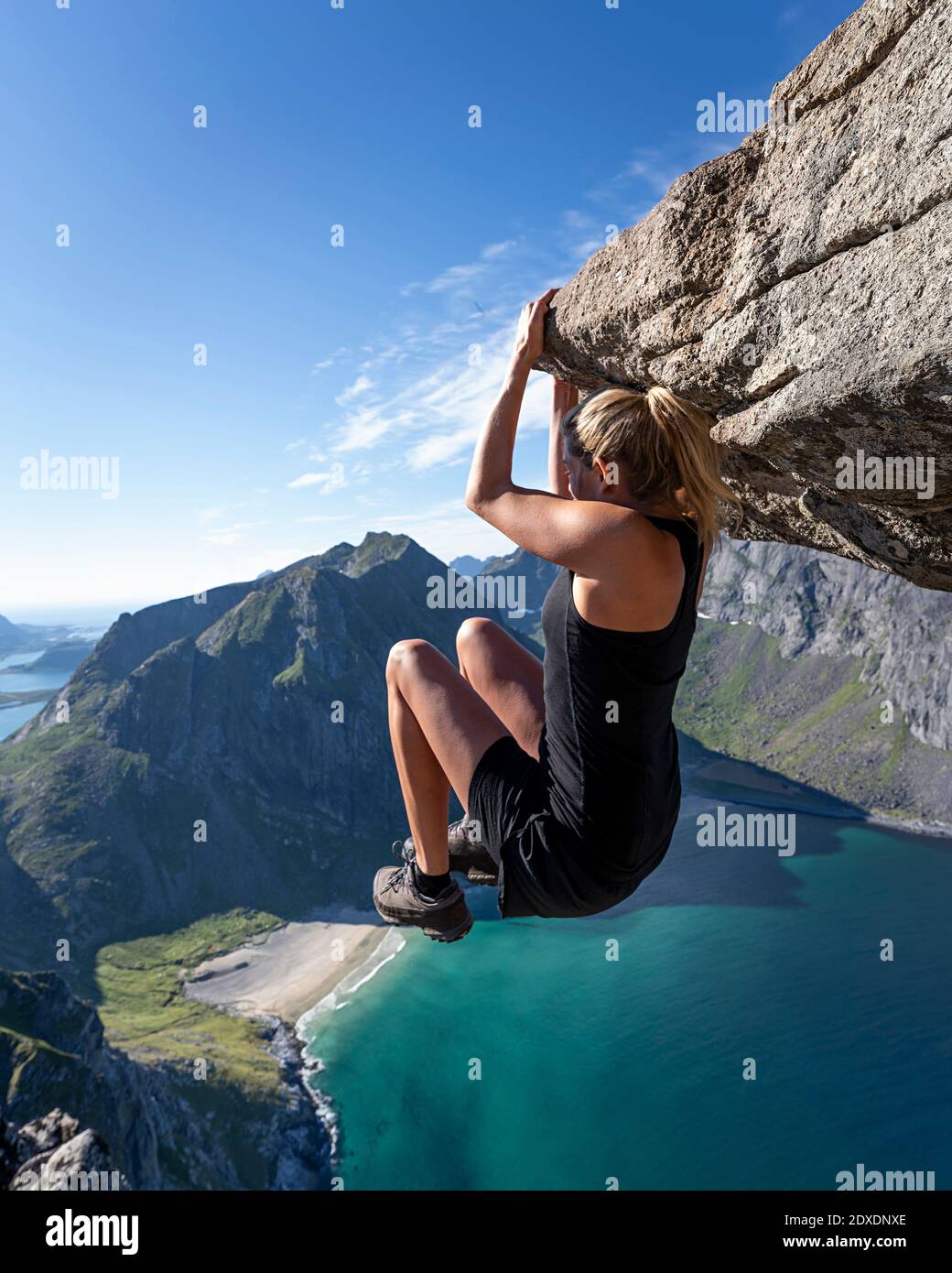 Donna appesa sul bordo della montagna a Ryten, Lofoten, Norvegia Foto Stock