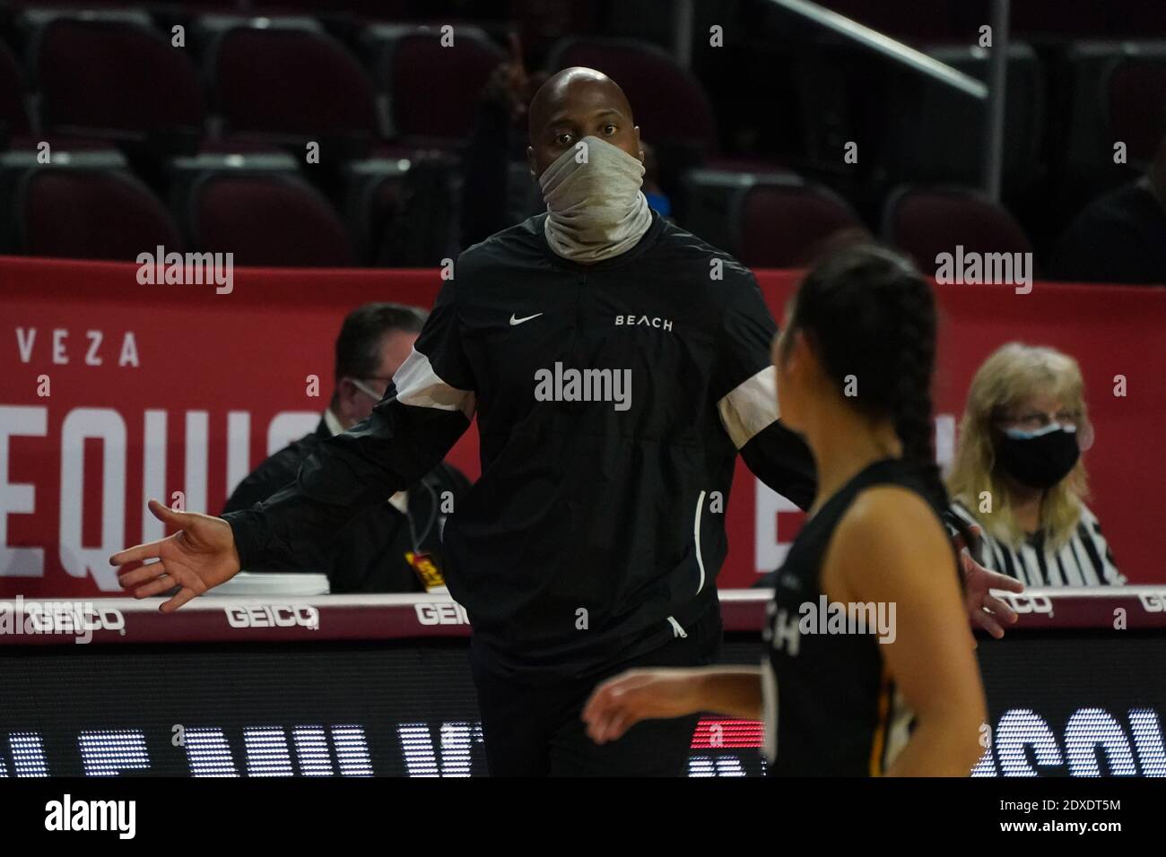 Il capo allenatore di Long Beach Jeff Cammon indossa un volto Maschera mentre gesturing verso la guardia Patricia Chung (30) durante un NCAA college femminile basket g Foto Stock