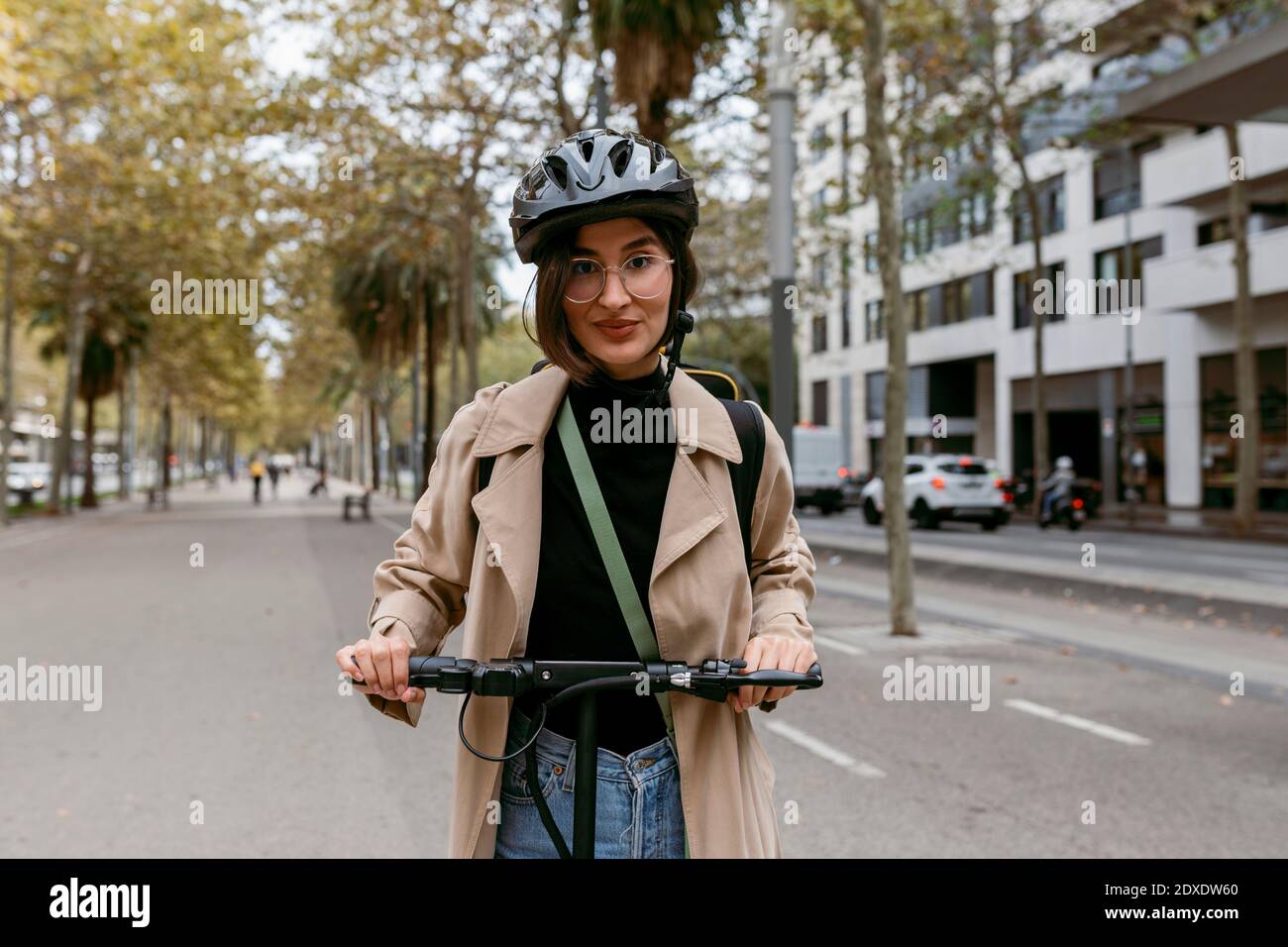 Donna mid adult in piedi con scooter elettrico a spinta su strada in città Foto Stock