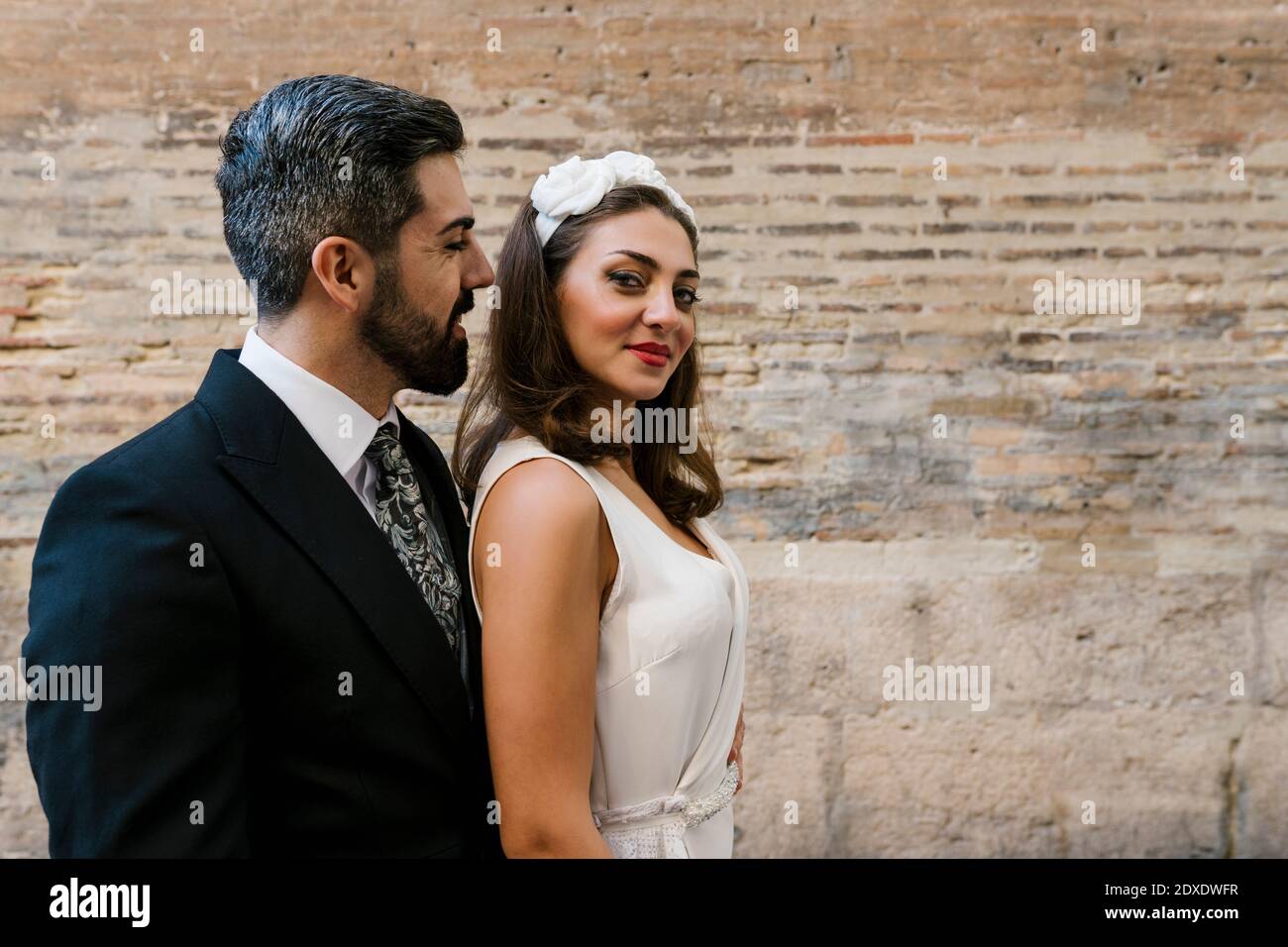 Felice coppia sposata in piedi a muro Foto Stock
