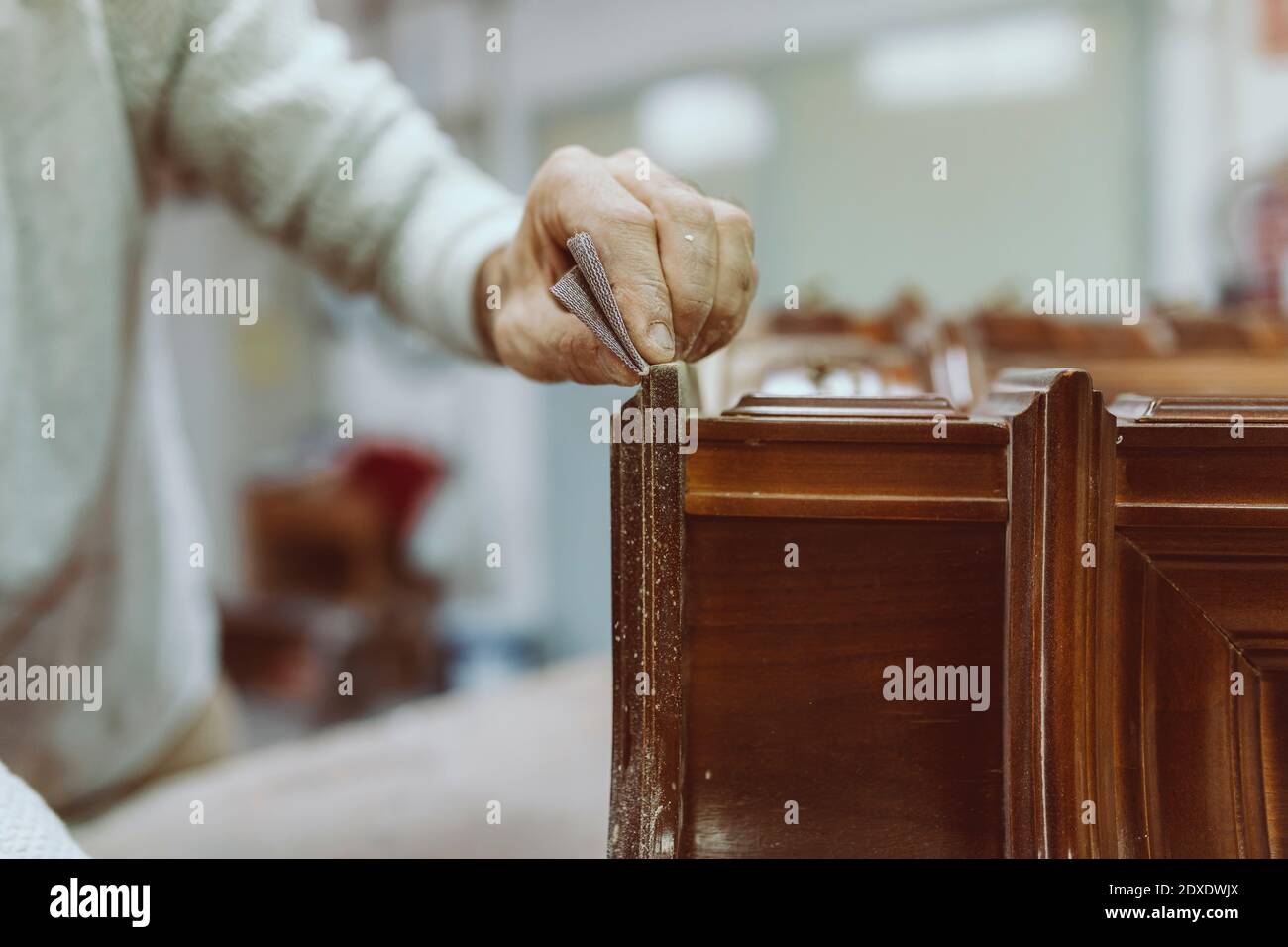 Lavoratore manuale strofinando carta di sabbia su mobili mentre lavorando a. officina Foto Stock