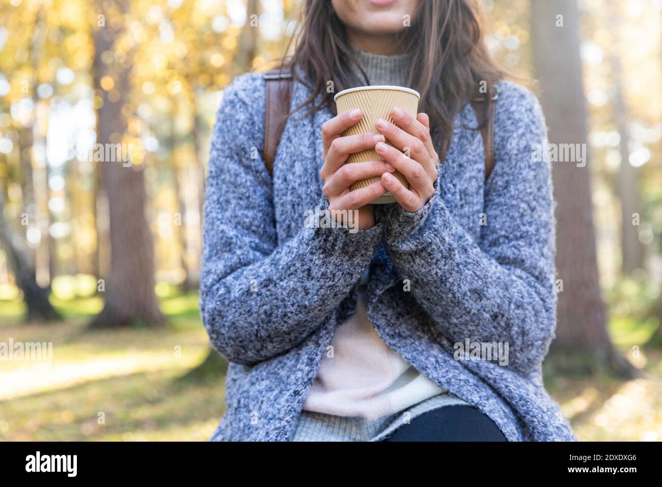 Donna che tiene una tazza da tè usa e getta nella foresta di Cannock Chase durante inverno Foto Stock