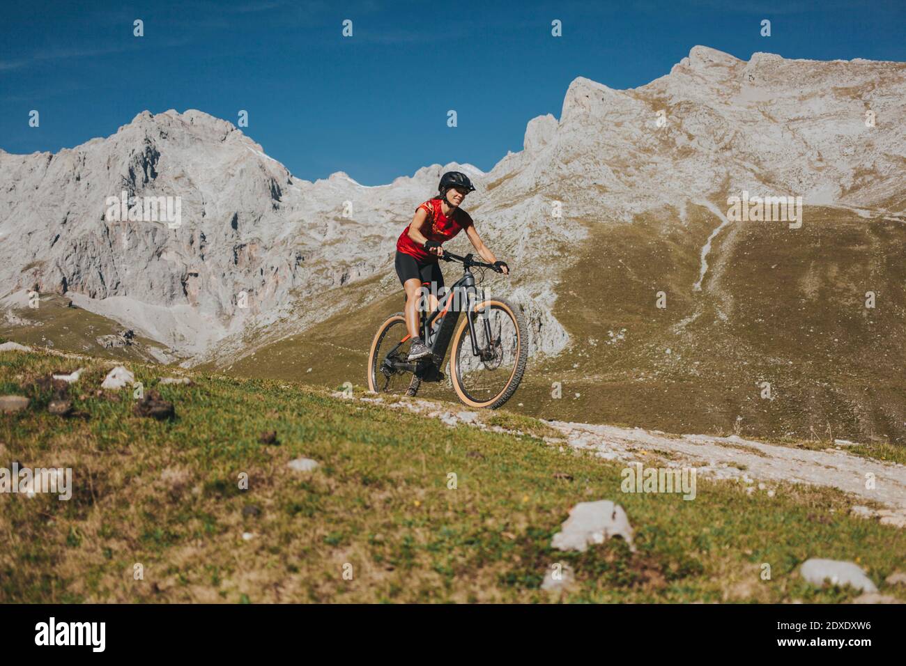 Ciclista femminile in mountain bike a cavallo sul sentiero del Parco Nazionale Picos de Europa, Cantabria, Spagna Foto Stock