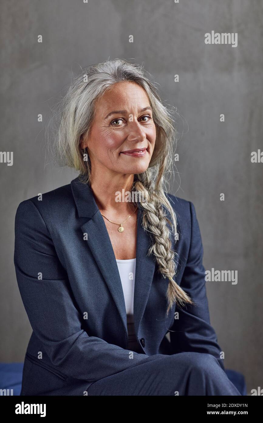 Sorridente professionista in affari casual contro parete grigia Foto Stock