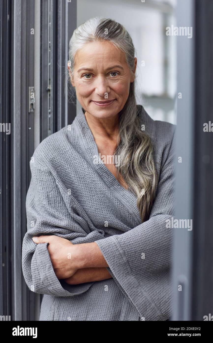 Donna matura sicura con le braccia incrociate in piedi in bagno Foto Stock