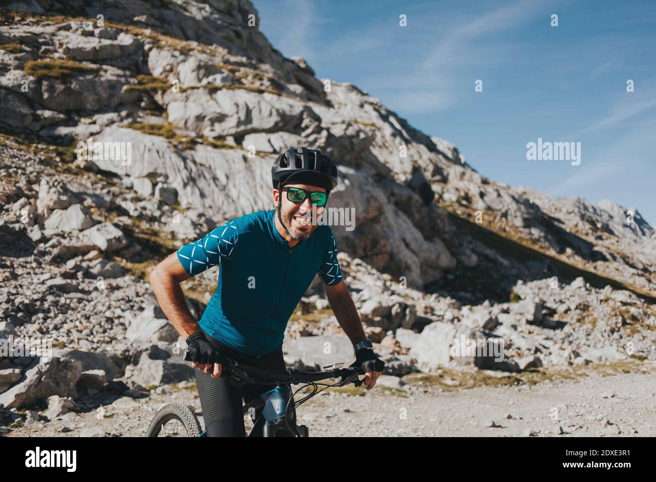 Allegro ciclista maschile in bicicletta contro la montagna durante la giornata di sole, Parco Nazionale Picos de Europa, Cantabria, Spagna Foto Stock