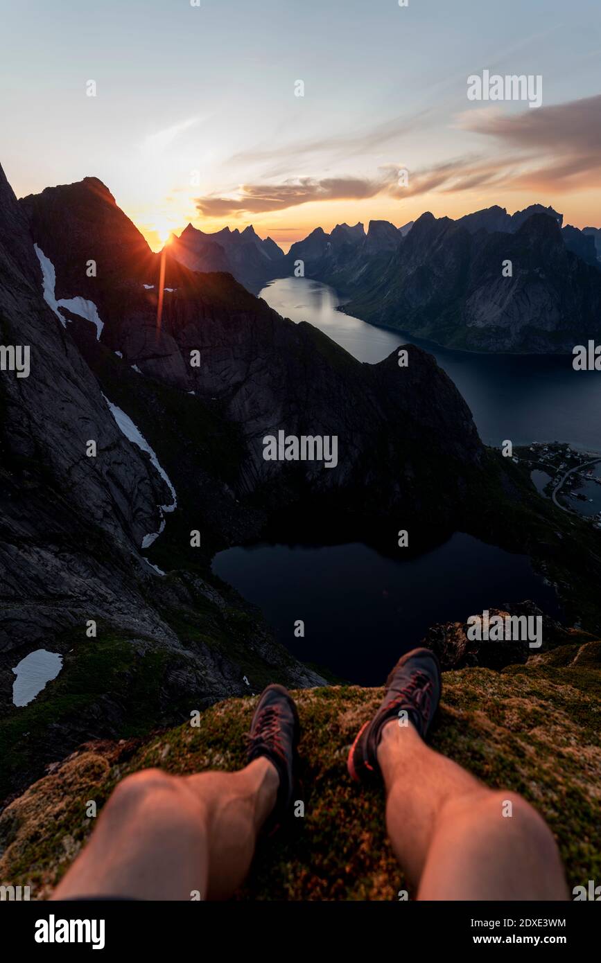 Uomo che indossa scarpe sportive seduto in montagna a Reinebringen. Lofoten, Norvegia Foto Stock