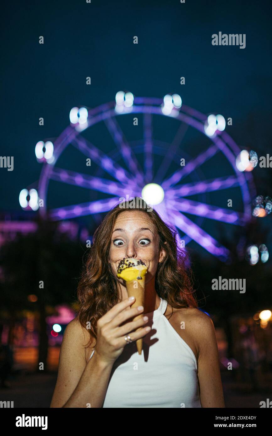 Donna che guarda il gelato mentre si trova contro la ruota dei traghetti in città Foto Stock