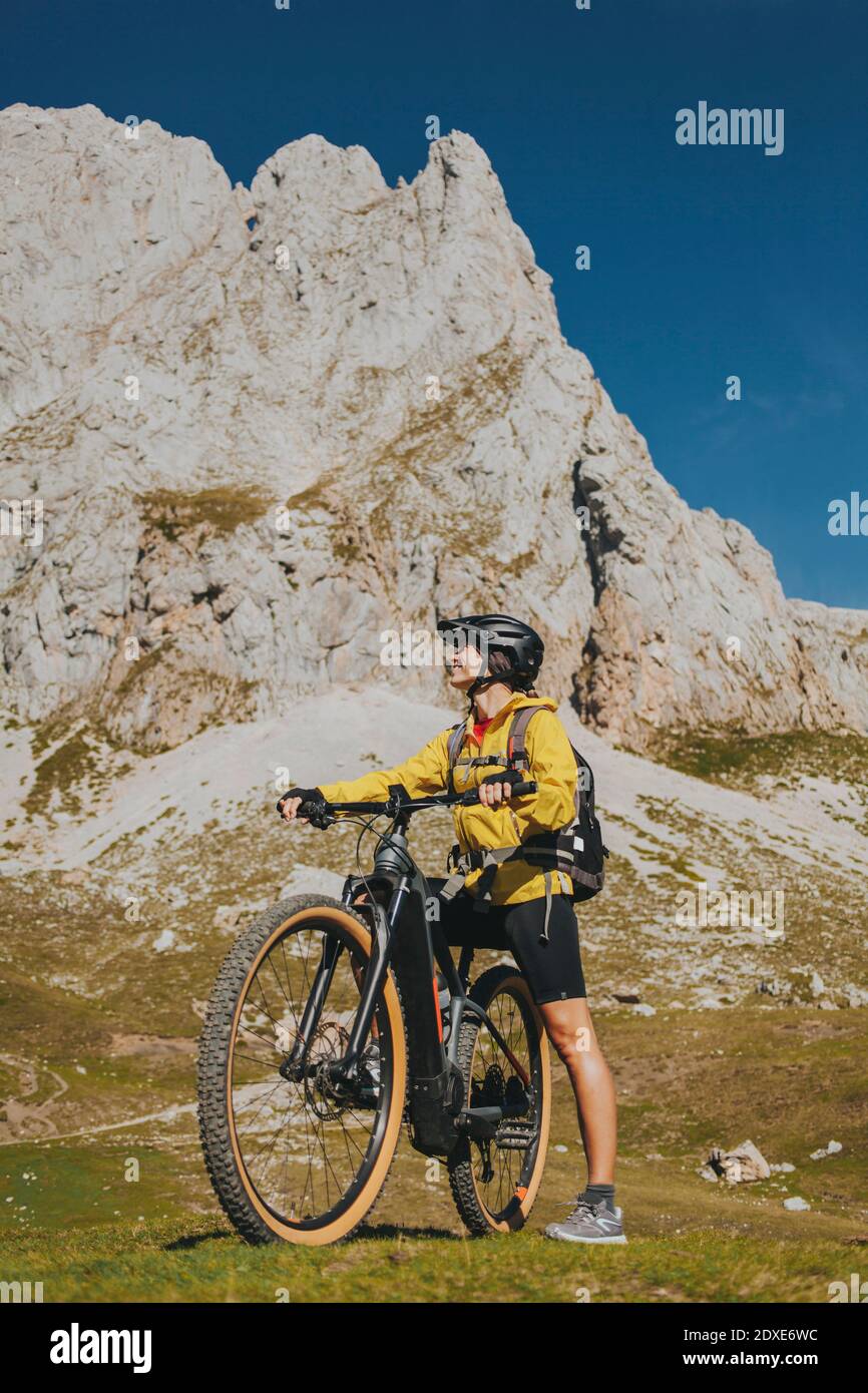Ciclista femminile con bicicletta contro la montagna rocciosa al Parco Nazionale Picos de Europa, Cantabria, Spagna Foto Stock