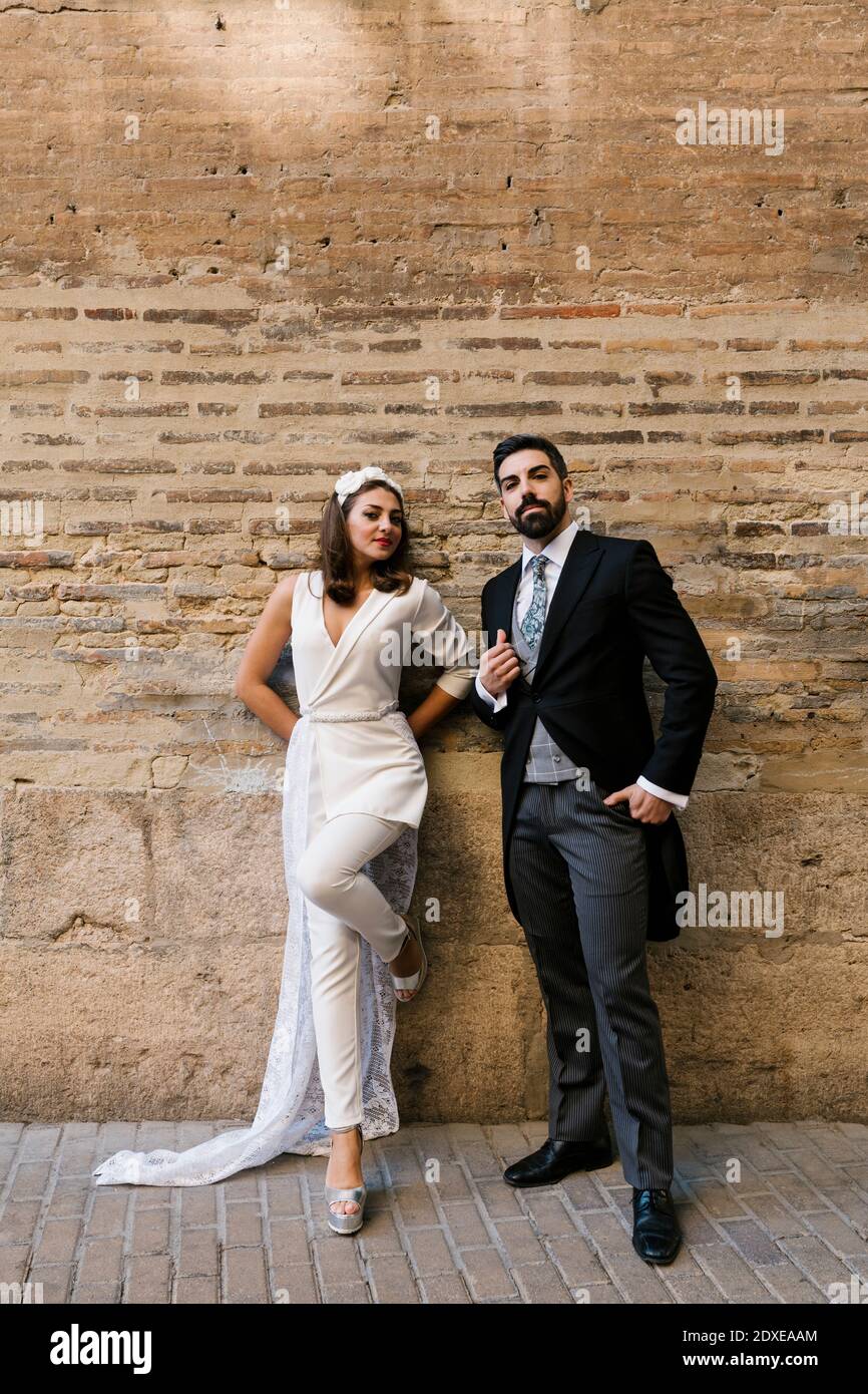 Giovane coppia appena sposata in piedi contro il muro sul sentiero Foto Stock