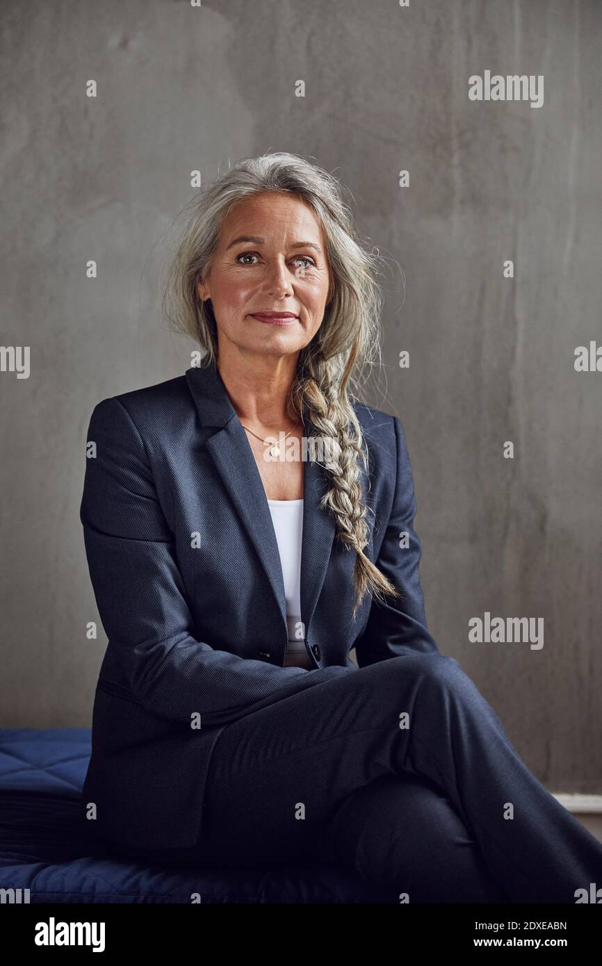 Donna d'affari sicura contro la parete grigia dell'ufficio domestico Foto Stock