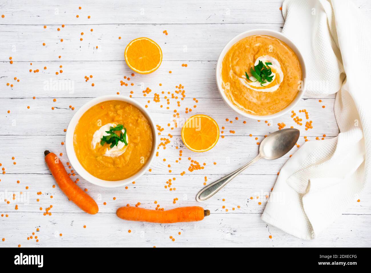 Due ciotole di zuppa vegetariana di lenticchie con carote, succo d'arancia, crema fraiche e prezzemolo Foto Stock