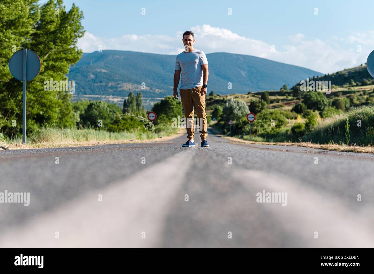 Giovane uomo in piedi in mezzo alla strada in giornata di sole Foto Stock