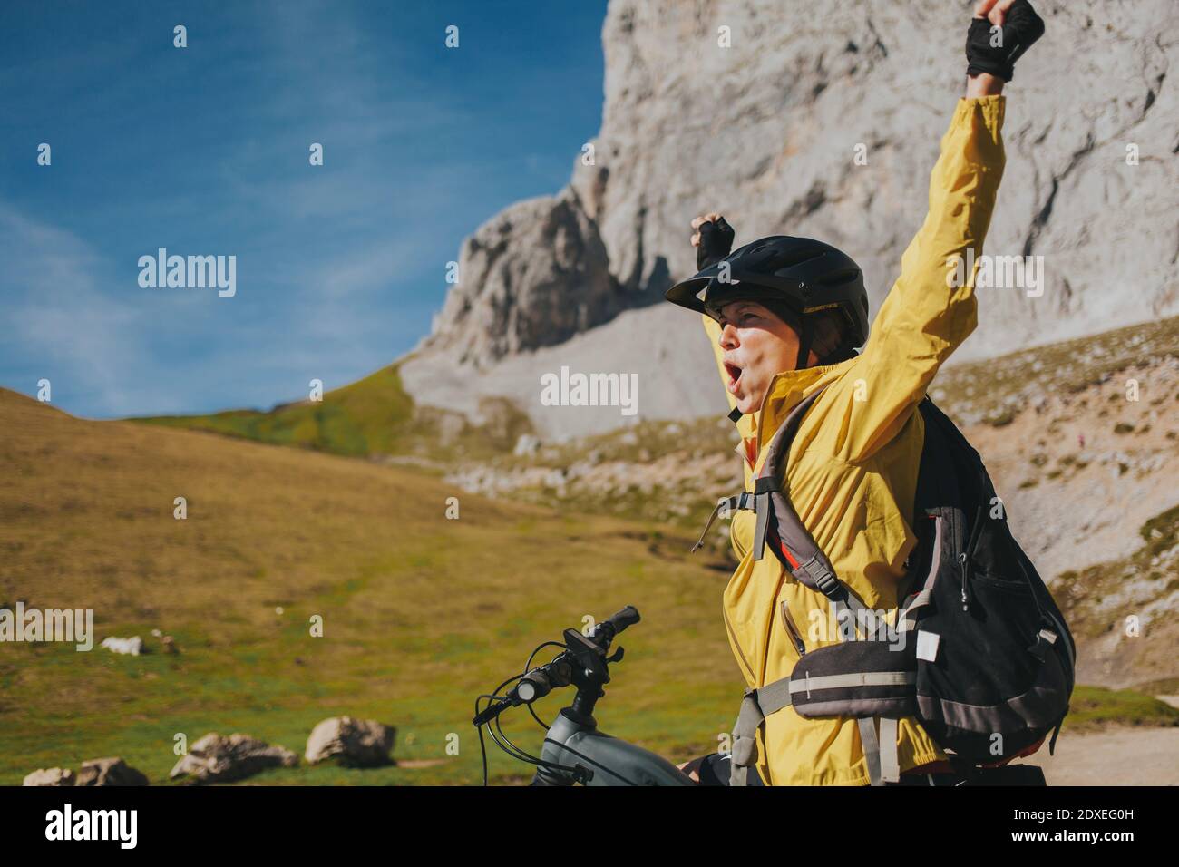 Eccitata ciclista femminile con armi che gridano al Parco Nazionale di Picos de Europa il giorno di sole, Cantabria, Spagna Foto Stock
